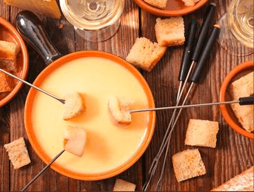 Traditionelles Schweizer Käsefondue im Hotel Wellenreiter an der Nordsee, serviert in gemütlicher Atmosphäre mit Brot und Wein – perfekter kulinarischer Winterabend in Nordfriesland.